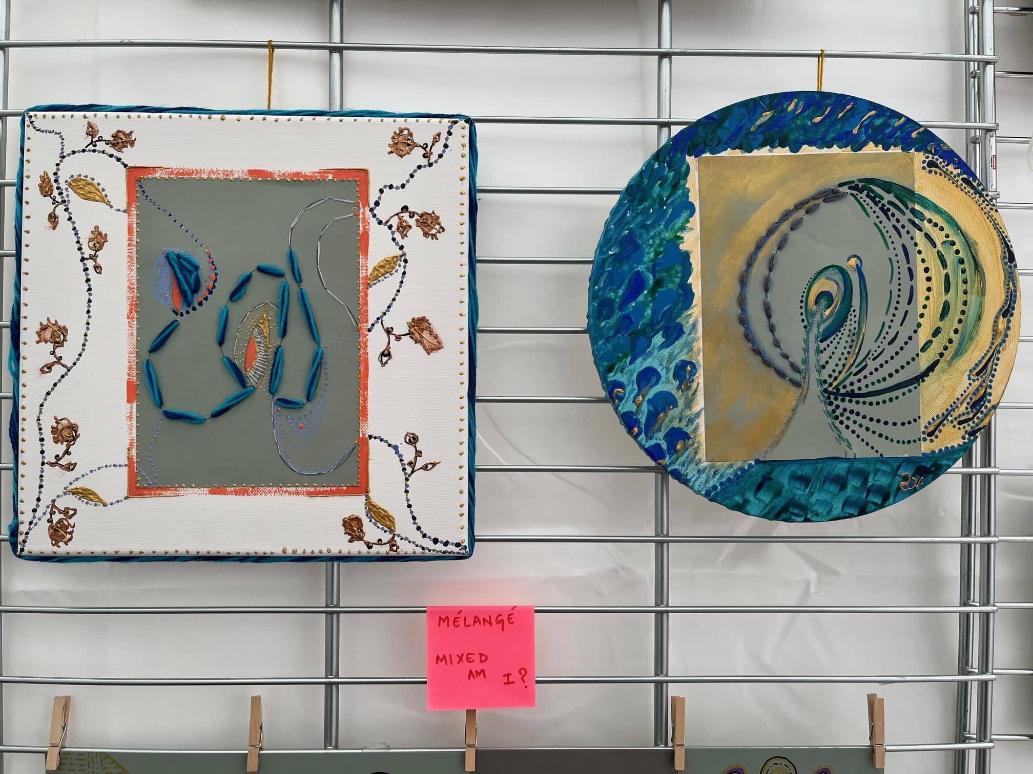 Des grains, Seedlings, 2024, av Anujalika. På en gallervägg: ett kvadratiskt verk med en broderad blå form innanför en bård av tryckt textil, och en rund panel av hällt blått och guldfärgat pigment med en prickad spiral.