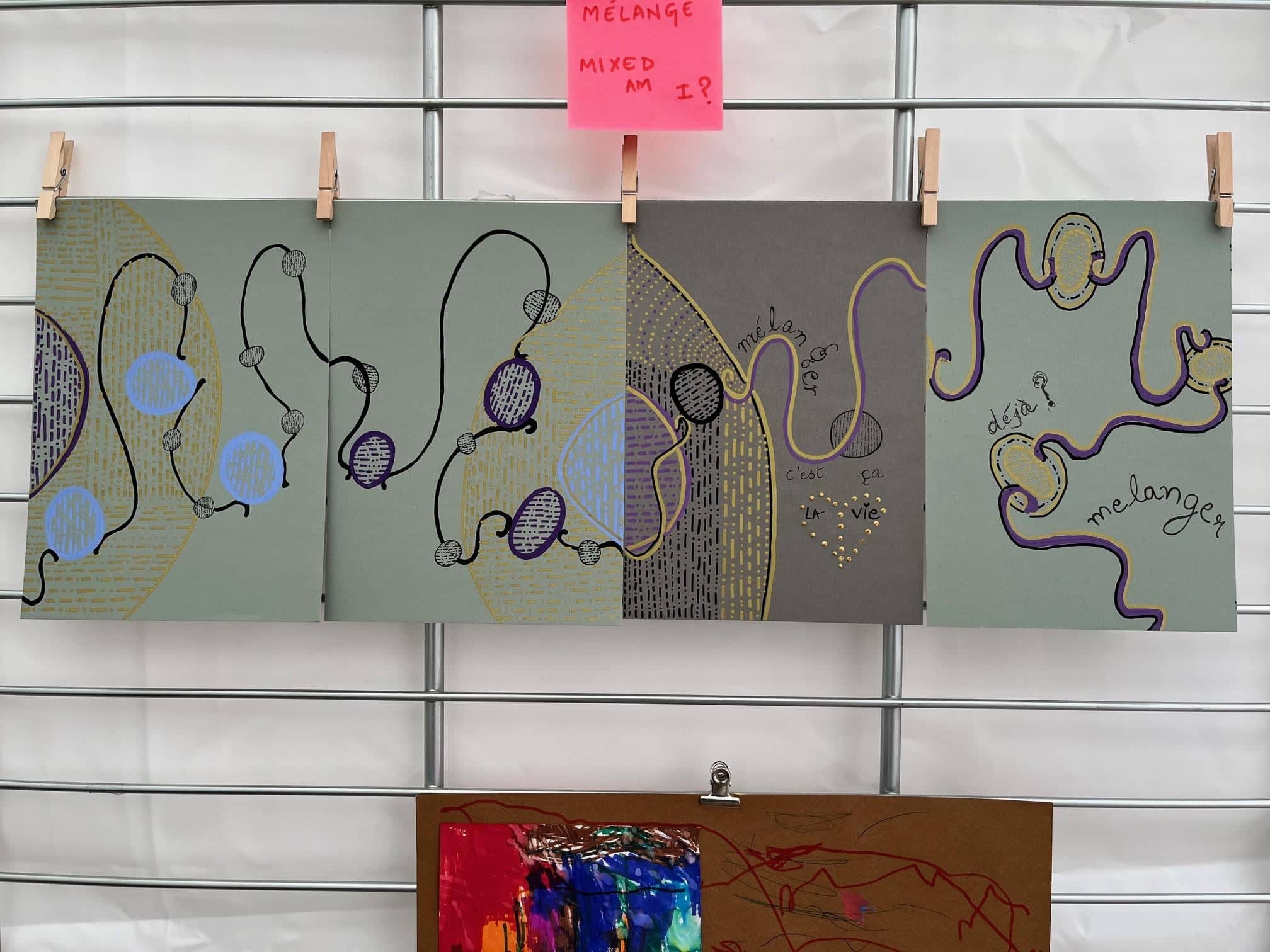 Mélanger, av Anujalika. Fem grå kartonger uppnålade på rad på ett galler, var och en broderad med slingrande linjer, blå och lila punkter och orden c'est ça la vie och mélanger.
